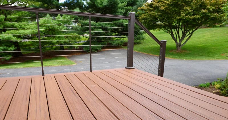 A composite deck featuring a sturdy metal railing and warm wooden decking, inviting for outdoor relaxation and gatherings.