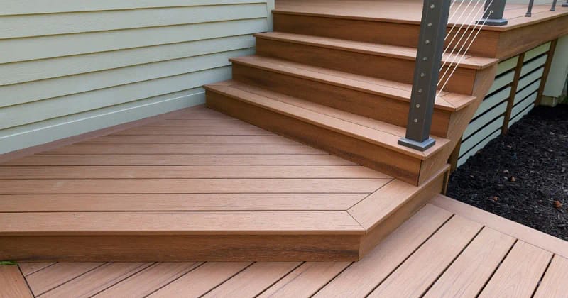 A composite deck featuring steps and a railing, providing a sturdy outdoor space for relaxation or gatherings.
